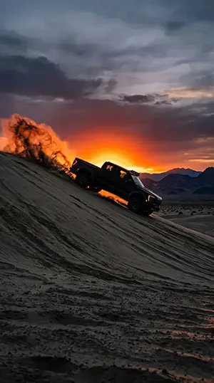 A ford raptor truck is in the desert during sunset time.